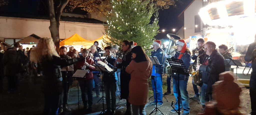 Musiker umgeben von Zuhörern spielen vor dem Weihnachtsbaum auf.